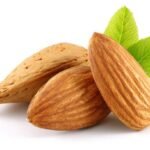 Almonds and green leaves isolated on white background